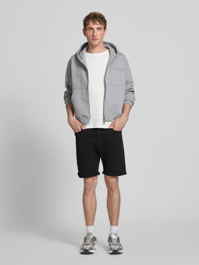 Männermodel trägt schwarze Jeansshorts mit Umschlag und Eingrifftaschen Modell 'RICK ALLEN' von Jack & Jones, Regular Fit, aus Baumwoll-Elasthan-Mix, Bundweite 43 cm, Innenbeinlänge 20 cm, Ganzkörperansicht von vorne