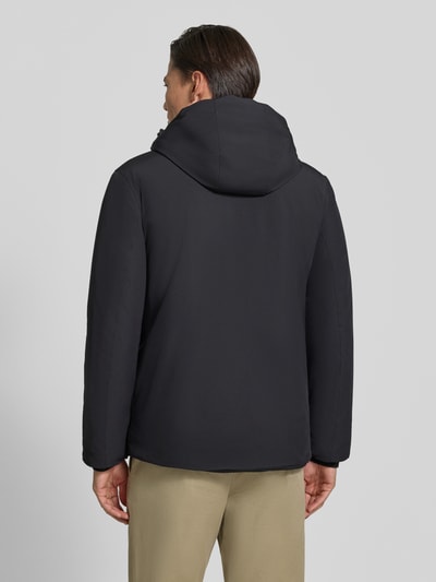 Männermodel trägt Regular Fit Jacke mit Logo-Print von Lindbergh aus elastyczna mieszanka materiałów, kolor czarny, kaptur z tunelem, Ganzkörperansicht Rückansicht. Długość tyłu w rozmiarze M: 74 cm, szerokość ramion w rozmiarze M: 46 cm, szerokość klatki piersiowej w rozmiarze M: 42 cm, długość rękawów: 62 cm.