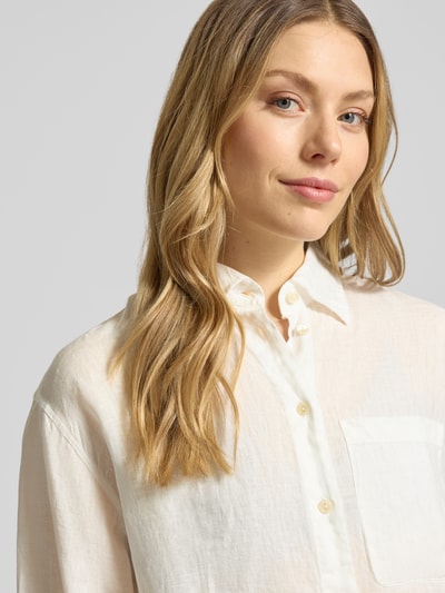 Frauenmodel trägt Relaxed Fit Longbluse aus Leinen Modell 'TAHIA' von 0039 Italy in Creme mit Hemdblusenkragen, Knopfleiste und Brusttasche, Nahaufnahme Oberkörper, reine Leinen, Rückenlänge bei Größe S 86 cm, Ärmellänge 58 cm.