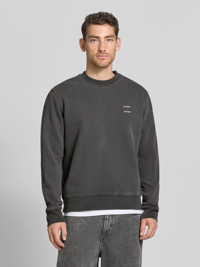 Männermodel trägt Sweatshirt mit Logo-Print Modell 'JOEL' von Samsøe Samsøe aus Baumwoll-Mix in Dunkelgrau, Relaxed Fit, Ganzkörperansicht von vorne