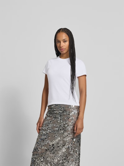 Frauenmodel trägt Slim Fit T-Shirt mit Rundhalsausschnitt von black palms aus reiner Baumwolle mit Logo-Detail, kurzärmelig, Rückenlänge 59 cm, Ganzkörperansicht von vorne.