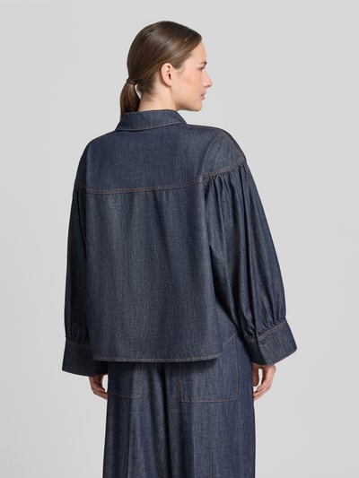 Modelka kobieca nosi Relaxed Fit Jeansbluse Modell 'SELENI' od Drykorn z czystej bawełny, ciemnoniebieska, widoczne przeszycia, koszulowy kołnierz, guzik, długość tyłu 64 cm, długość rękawa 57 cm w rozmiarze 36, widok całej sylwetki z tyłu