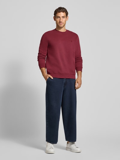 Männermodel trägt Regular Fit Sweatshirt aus reiner Baumwolle Modell 'BAARO' von ARMEDANGELS in Dunkelrot, Ganzkörperansicht von vorne. Herren Sweatshirt.