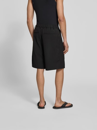 Männermodel trägt schwarze Shorts mit Viskose-Anteil von Don’t Waste Culture, teilelastischer Bund, Gesäßtaschen, Relaxed Fit, Ganzkörperansicht Rückansicht.