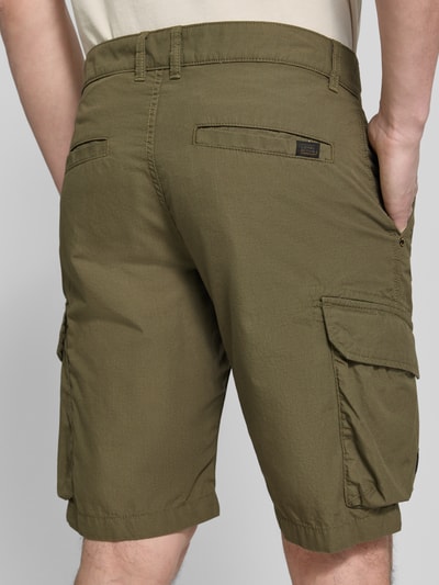 Männermodel trägt Bermudas mit Cargotaschen von camel active in olivgrün, reine katoen, regular fit, cargozakken, labeldetail, detailaufnahme Rückansicht.