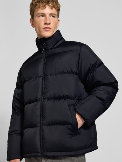Männermodel trägt schwarze Regular Fit Steppjacke mit Label-Patch Modell 'ROCKWELL' von Levi's®, Herren Steppjacke, Ganzkörperansicht von vorne.