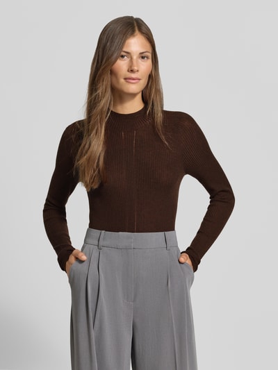 Frauenmodel trägt Strickpullover mit Woll-Anteil von MYON, braun, Stehkragen, Ripp-Optik, Lochmuster, eng, Ganzkörperansicht von vorne.