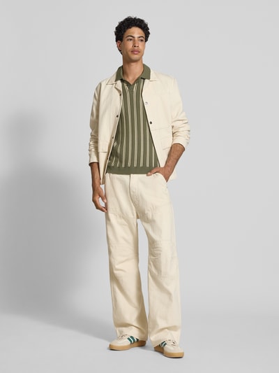 Männermodel trägt Regular Fit Strick-Poloshirt Modell 'POUL' von Redefined Rebel aus Baumwoll-Mix in Olivgrün mit Knopfleiste, Ganzkörperansicht von vorne.