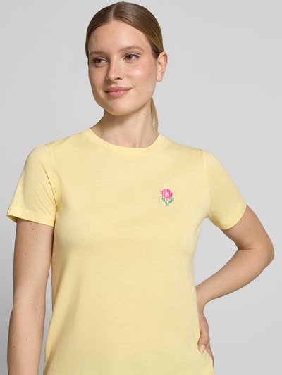 Frauenmodel trägt Damen T-Shirt mit floralem Stitching Modell 'Aminna' von ICHI in Gelb aus Reine Baumwolle, Nahaufnahme Oberkörper.