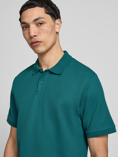 Männermodel trägt Regular Fit Poloshirt mit Strukturmuster Modell 'AUSTIN' von Jack & Jones in Grün, Material-Mix, Nahaufnahme Oberkörper.