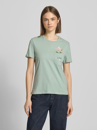 Frauenmodel trägt Regular Fit T-Shirt aus reiner Bio-Baumwolle Modell 'POLLY' von Only, Optik: Unifarben, Jersey, Statement-Print-Applikation, Rundhals, Kurzarm, Brusttasche mit Motiv-Stitching und versteckter Botschaft, Ganzkörperansicht von vorne.