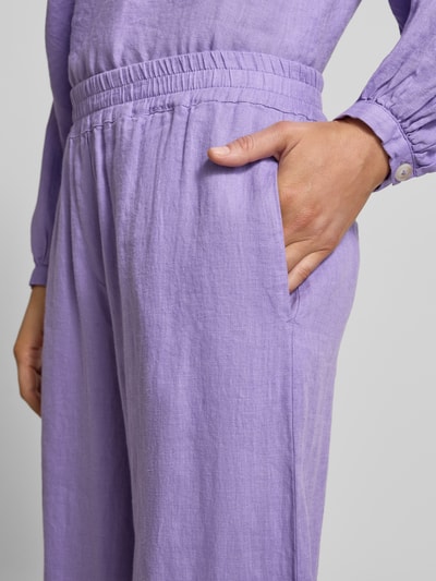 Vrouwenmodel draagt Leinenhose met elastischem Bund van Emily Van den Bergh in lichtpaars linnen met elastische band en paspelzakken achter, detailopname heup.