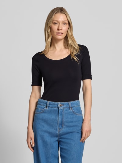 Kobiece model nosi T-Shirt mit Ärmelaufschlag und Rundhalsausschnitt od Marc Cain, mieszanka bawełny z dodatkiem streczu, dopasowany krój, okrągły dekolt, rękawy z zakładką, detal z logo, długość tyłu w rozmiarze 36: 60 cm, kolor czarny, gładka faktura, całkowite widoczne z przodu, zdjęcie całej sylwetki z przodu.
