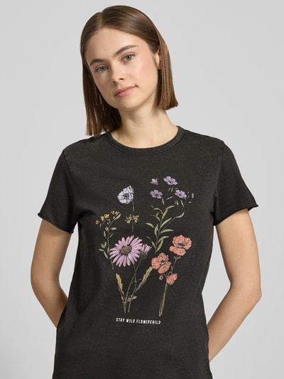 Modelka kobieca ma na sobie Regular Fit T-Shirt aus reiner Baumwolle Modell 'LUCY' od Only, czarny kolor, nadruk z motywem kwiatowym, krótki rękaw, okrągły dekolt, jersey, przód, zbliżenie na górną część ciała.