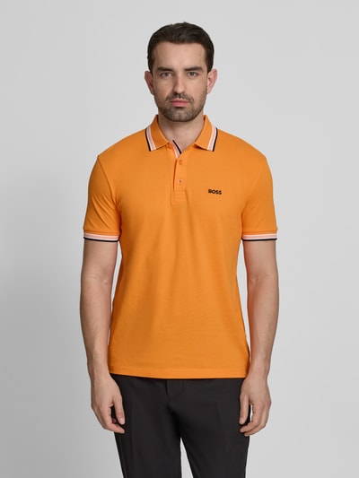 Männermodel trägt Regular Fit Poloshirt aus reiner Baumwolle Modell 'PADDY' von BOSS Green in Optik: Unifarben mit Label-Print, Polokragen, 3-Knopf-Verschluss, Ärmelform: Kurzarm, Materialverarbeitung: Piqué, Ganzkörperansicht von vorne.