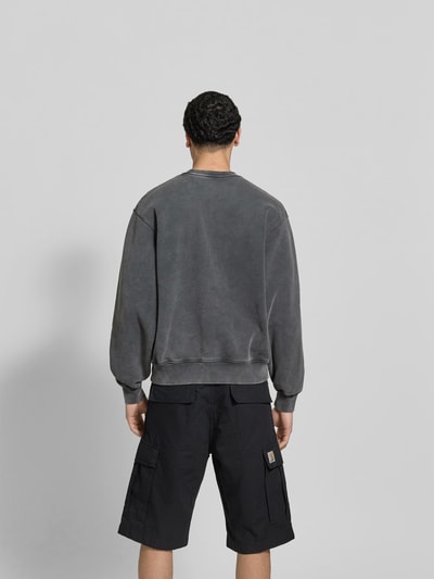 Männermodel trägt Oversized Hoodie aus Baumwoll-Mix von MAISON KITSUNÉ in Grau mit Used-Look und elastischen Abschlüssen, Ganzkörperansicht Rückansicht.