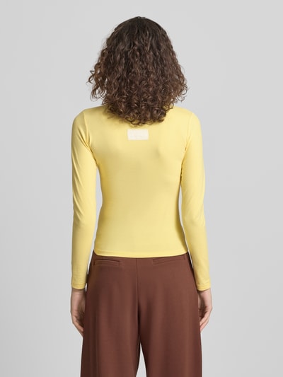 Frauenmodel trägt Slim Fit Longsleeve mit Logo-Detail von ANOTHER COTTON LAB in Gelb aus elastischem Baumwoll-Mix, Rückenansicht Ganzkörperansicht.