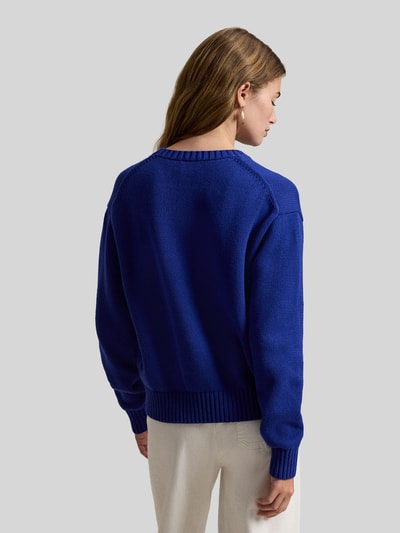 Frauenmodel trägt Regular Fit Strickpullover mit Polo-Bear-Intarsia von Polo Ralph Lauren in Unifarbe Blau aus reiner Baumwolle, Ganzkörperansicht Rückansicht.