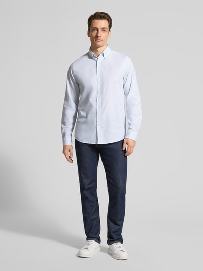 Männermodel trägt Regular Fit Freizeithemd aus reiner Bio-Baumwolle Modell 'QUAASA' von Armedangels in Hellblau, Ganzkörperansicht von vorne. Unifarben, Button-Down-Kragen, einreihige Knopfleiste, langarm, Kombimanschette, leicht abgerundeter Rumpfabschluss, Logo-Detail.
