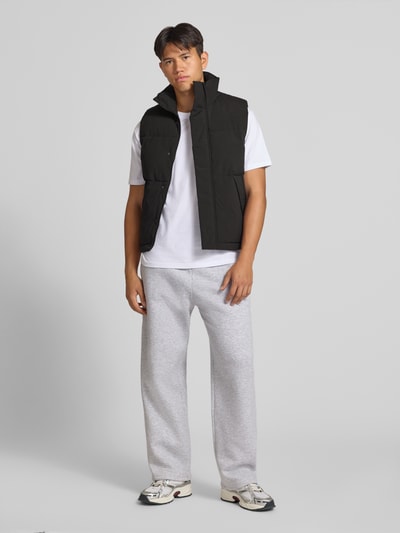 Mannenmodel draagt zwarte bodywarmer met opstaande kraag van JACK & JONES Model 'SOHO BODYWARMER', regular fit, voorkant, ruglengte maat M 65 cm, schouderbreedte 43 cm, borstwijdte 59 cm. Ganzkörperansicht von vorne.