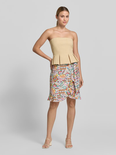 Frauenmodel trägt Wickelrock aus Viskose-Mix im Allover-Look von Christian Berg Woman, mehrfarbig, A-Linie, Minirock, Ganzkörperansicht von vorne.