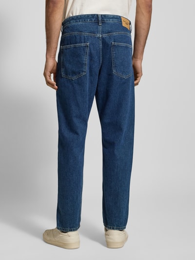 Männermodel trägt Tapered-Fit Herren Jeans aus reiner Baumwolle Modell 'RUNNA' von Marc O'Polo Denim, Denim-Optik, Ganzkörperansicht Rückansicht.
