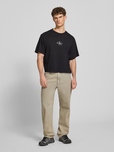 Männermodel trägt Relaxed Fit T-Shirt aus reiner Baumwolle von Calvin Klein Jeans in Optik: Unifarben, Label-Print, Kurzarm, Jersey, Ganzkörperansicht von vorne.