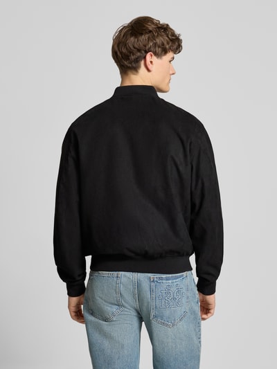 Männermodel trägt Bomberjacke mit Reißverschluss von REVIEW in Schwarz, gerippte Abschlüsse, regular fit, ganzkörperansicht rückansicht