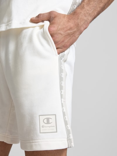 Männermodel trägt Shorts mit Logo und elastischem Bund von CHAMPION in Cremeweiß, Baumwoll-Mix, Regular Fit, Nahaufnahme Oberschenkel.