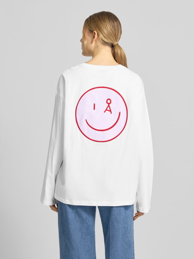 Frauenmodel trägt Oversized Langarmshirt aus reiner Baumwolle Modell 'FIETAA SMILE' von Armedangels, Optik: Unifarben, Passform: Oversized, Logo-Stitching und Label-Schriftzug, Feinripp-Textur, Ganzkörperansicht Rückansicht.