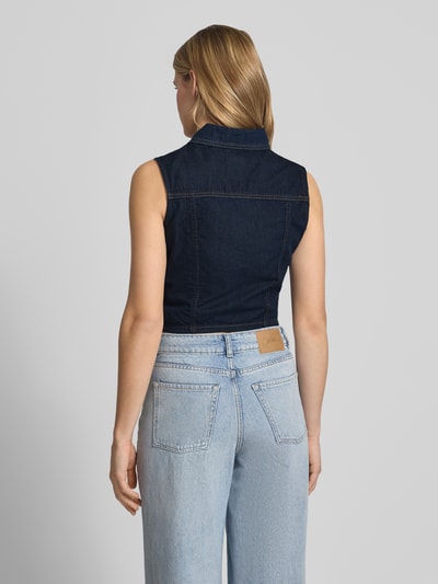 Frauenmodel trägt Cropped Jeansbluse mit Label-Patch von Guess Jeans in dunklem Blau aus Reine Baumwolle, Körpernaher-Schnitt, Kentkragen, Knopfleiste, Rückenlänge bei Größe S 43 cm, Ganzkörperansicht Rückansicht.