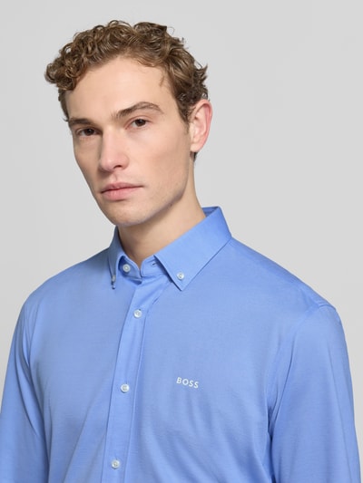 Männermodel trägt Regular Fit Businesshemd aus Pinpoint mit Stretch-Anteil von BOSS in Blau, Baumwoll-Mix, Logo-Schriftzug, Nahaufnahme Oberkörper.