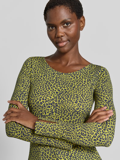 Frauenmodel trägt Longsleeve im Allover-Look mit Rundhalsausschnitt von Marc Cain, gelb-schwarzes Muster, Material-Mix, Slim Fit, Nahaufnahme Oberkörper.
