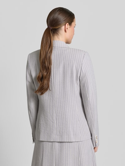 Vrouwenmodel draagt Regular Fit Blazer aus Seersucker mit Streifen und Lurex van Christian Berg Woman Selection, lichtgrijs met witte strepen, gestructureerde stof, reverskraag, paspelzakken, knoopsluiting, ruglengte 63 cm, buste 39 cm, mouwlengte 63 cm, volledige lichaamsweergave achteraan.