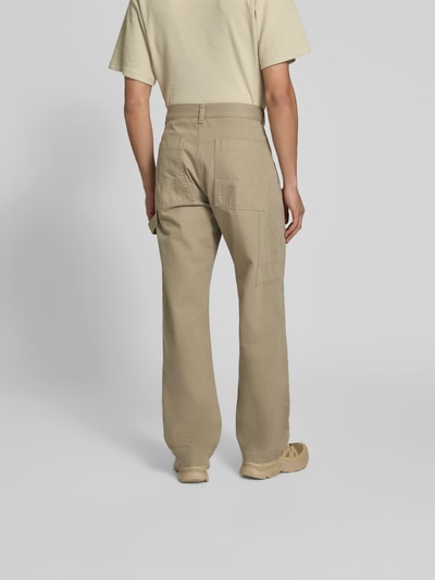 Männermodel trägt Straight Fit Jeans mit Gesäßtaschen von Forét aus Reine Baumwolle in Beige, sichtbare Nähte, Ganzkörperansicht Rückansicht.