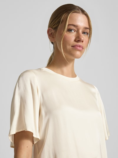 Modelka nosi T-Shirt aus Viskose-Mix mit Rundhalsausschnitt von comma, kremowy kolor, prosty krój, półrękaw, viskoza ze stretchem, zbliżenie na górną część ciała, widok z przodu.