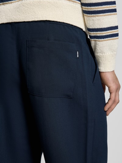Männermodel trägt Straight Fit Stoffhose mit Viskose-Anteil von REVIEW, navyblau, elastischer Bund, Gesäßtasche, Detailaufnahme Rückansicht.