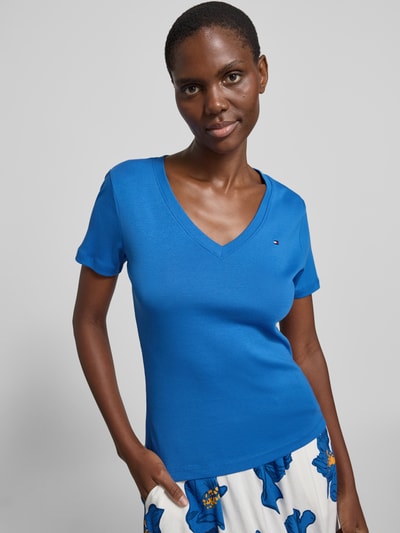 Kobiece model prezentuje damski t-shirt Slim Fit T-Shirt aus reiner Baumwolle od Tommy Hilfiger, efekt: jednolity kolor, krój slim fit, wyhaftowane logo, dekolt w serek, krótki rękaw, wykończenie materiału: dżersej, materiał: czysta bawełna; ujęcie: z przodu, górna część ciała.