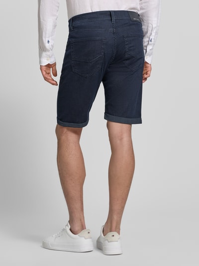 Männermodel trägt Jeansshorts mit Label-Detail von Pierre Cardin in Dunkelblau, Baumwoll-Mix mit Stretch-Anteil, Ganzkörperansicht Rückansicht. Regular-Fit, Eingrifftaschen, Umschlag, Bundweite bei Größe 32: 42 cm, Innenbeinlänge bei Größe 32: 26 cm.