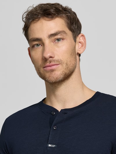 Männermodel trägt Regular Fit T-Shirt aus reiner Baumwolle von s.Oliver RED LABEL, Optik: Unifarben, Henley-Kragen, Ärmelform: Kurzarm, Nahaufnahme Oberkörper.