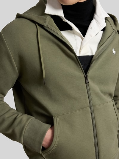 Männermodel trägt regular fit sweatjack van katoenmix van Polo Ralph Lauren in olijfgroen, nahaufnahme bovenlichaam.