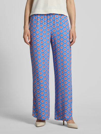 Frauenmodel trägt Wide Fit Stoffhose aus reiner Viskose mit Allover Motiv-Print von Smith and Soul, blau-rote Muster, elastischer Bund, Nahaufnahme Unterkörper.