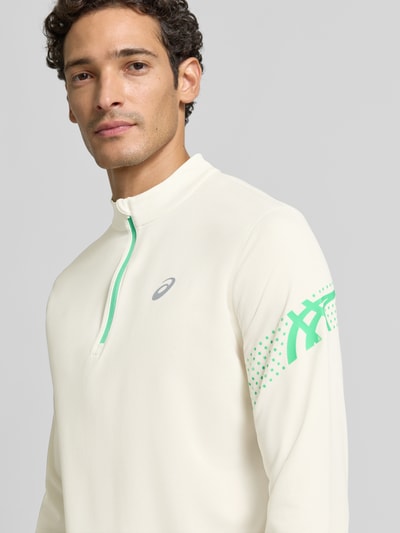 Męski model nosi bluzkę z długim rękawem z kołnierzem zapinanym, nadruk z logo, beż i zieleń, Model 'ICON' od ASICS TIGER, krój prosty, Długość tyłu w rozmiarze M: 72 cm, zbliżenie na górną część ciała