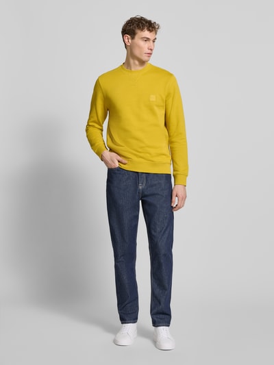 Männermodel trägt Relaxed Fit Sweatshirt aus reiner Baumwolle Modell 'WESTART' von BOSS Orange in Gelb, unifarben, Label Patch, Ganzkörperansicht von vorne