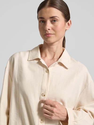 Modelka kobieca nosi Relaxed Fit Hemdjacke aus Baumwoll-Leinen-Mix Modell 'Formente' od OPUS, kołnierzyk koszulowy, listwa guzikowa, mieszanka bawełny i lnu, kolor jasny beż, długość tyłu 44 cm, długość rękawów 52 cm w rozmiarze 36, tekstura gładka, zbliżenie na górną część ciała