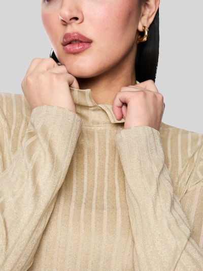 Frauenmodel trägt Longsleeve mit Rollkragen von Marc Cain aus Viskose-Mix mit Glitzer-Garn, Ripp-Struktur, Nahaufnahme Oberkörper.
