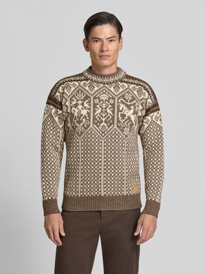 Männermodel trägt Strickpullover mit Stehkragen von Dale of Norway in Braun mit Muster, gerader Schnitt, Label-Patch, Ganzkörperansicht von vorne.