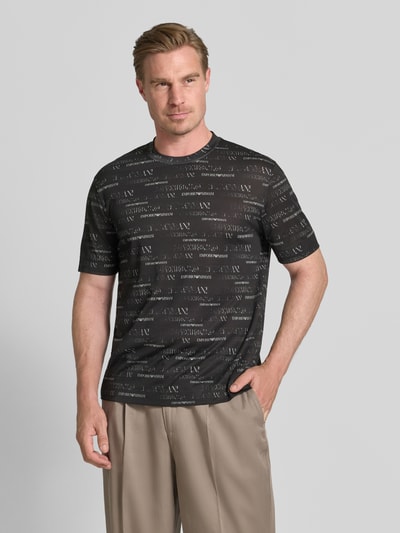 Männermodel trägt T-Shirt mit Logo-Muster und Rundhalsausschnitt von Emporio Armani im Lyocell-Baumwoll-Mix, Regular-Fit, Herren T-Shirt, Rückenlänge 70 cm bei Größe M, Ganzkörperansicht von vorne.