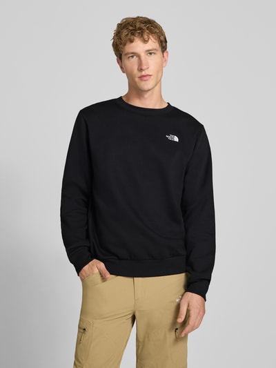 Männermodel trägt Regular Fit Sweatshirt Modell "EVOLUTION" von The North Face in Schwarz, Baumwoll-Mix, Logo-Stitching, Ganzkörperansicht von vorne.