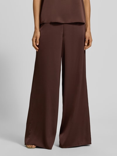 Frauenmodel trägt Wide Fit Stoffhose aus Satin von VM by Vera Mont in Dunkelbraun, glatte Textur, teilelastischer Bund, Nahaufnahme Oberkörper. Damen Stoffhose, Satin, Wide Fit, Bundfalten, Bundweite 38 cm, Innenbeinlänge 83 cm bei Größe 36.